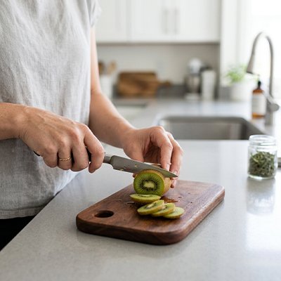 Planche à découper bois dame préparant collation tranchant kiwi
